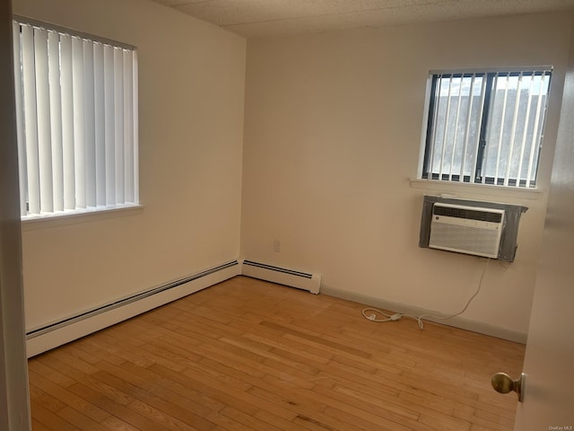 empty room with light hardwood / wood-style flooring, baseboard heating, and an AC wall unit