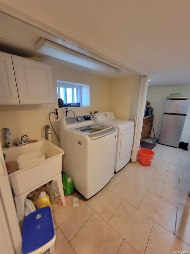 laundry area featuring cabinets, light tile patterned floors, and washing machine and clothes dryer