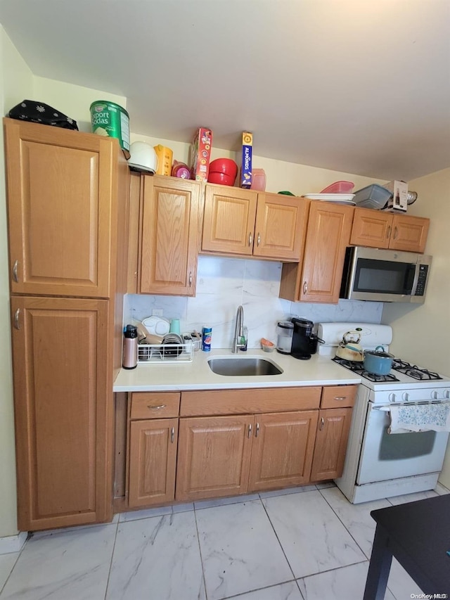 kitchen featuring backsplash, white range with gas cooktop, and sink