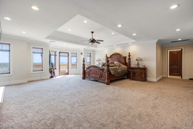 carpeted bedroom with a tray ceiling, ornamental molding, multiple windows, and access to exterior