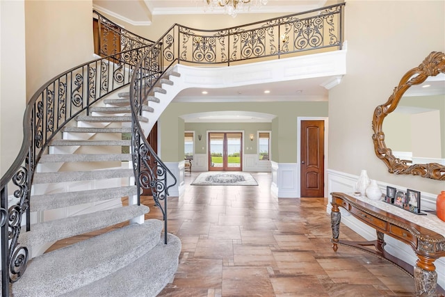 entryway featuring a towering ceiling and crown molding