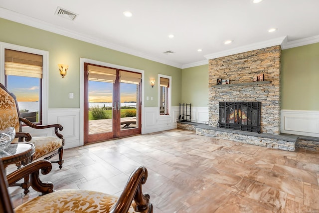 living room with ornamental molding, a stone fireplace, and plenty of natural light