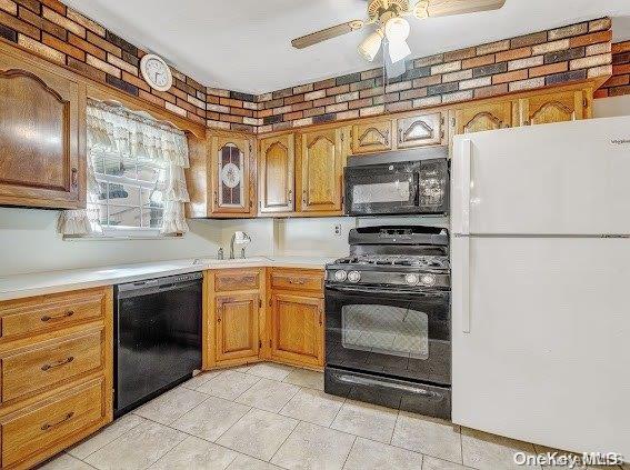 kitchen with ceiling fan, black appliances, and brick wall