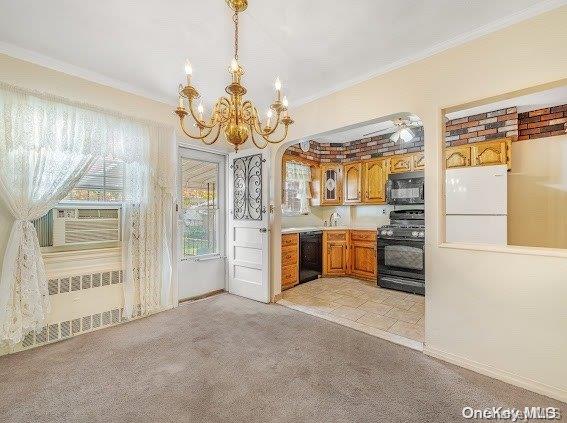 kitchen featuring pendant lighting, crown molding, and black appliances