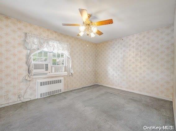 unfurnished living room with ceiling fan, radiator heating unit, and carpet