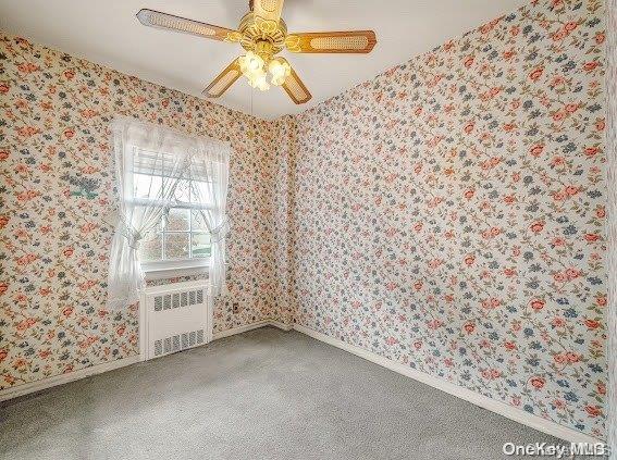 carpeted spare room with radiator heating unit and ceiling fan