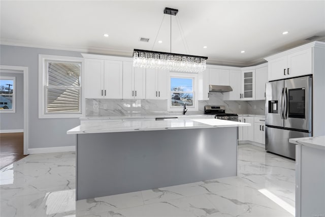 kitchen with white cabinets, appliances with stainless steel finishes, a center island, and hanging light fixtures