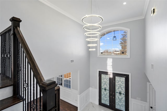 entryway with french doors, crown molding, and a notable chandelier