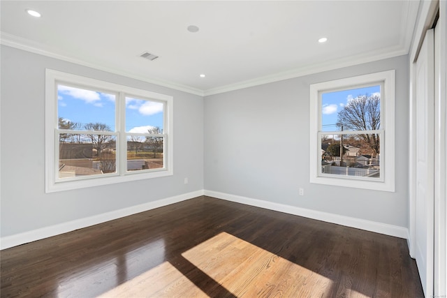 empty room featuring a wealth of natural light, crown molding, and dark wood-type flooring