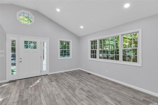 entryway with light wood-type flooring, high vaulted ceiling, and a wealth of natural light