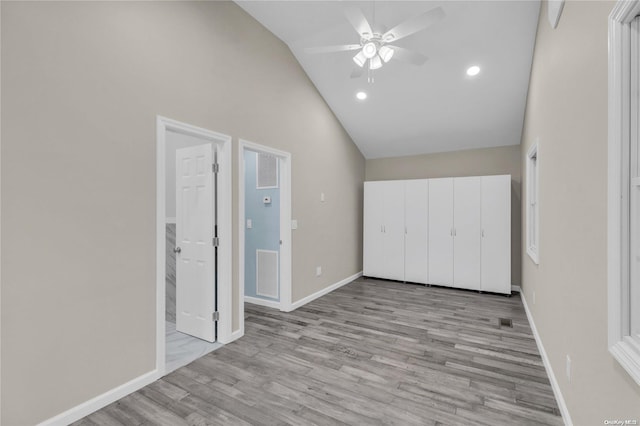 unfurnished bedroom with ceiling fan, high vaulted ceiling, and light hardwood / wood-style flooring