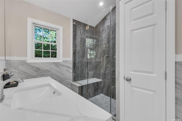 bathroom featuring vanity, a shower with shower door, and tile walls