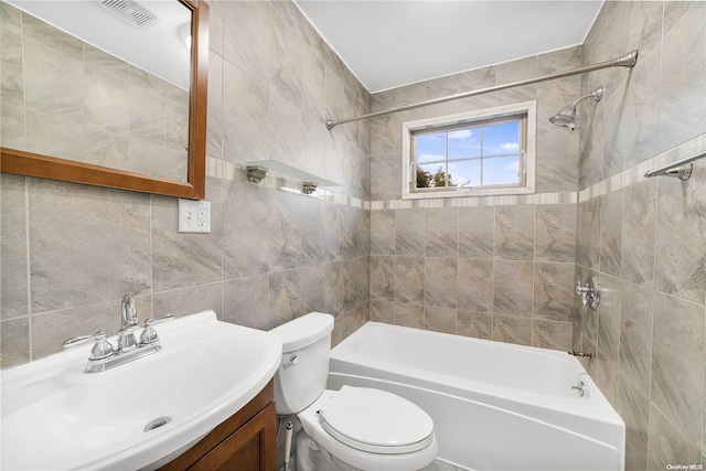 full bathroom with vanity, toilet, tile walls, and tiled shower / bath