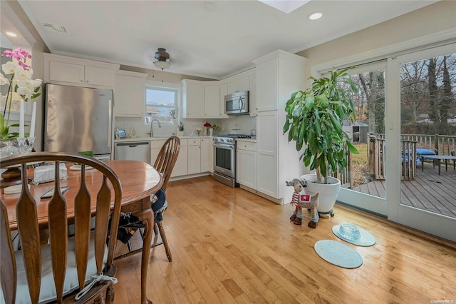 kitchen featuring white cabinets, stainless steel appliances, ceiling fan, and light hardwood / wood-style floors