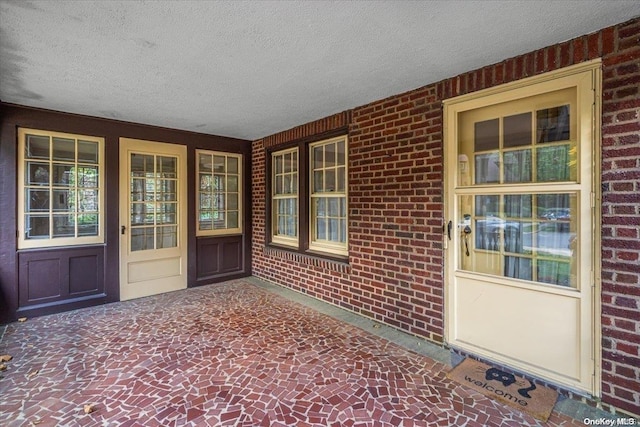 view of exterior entry featuring a porch and brick siding