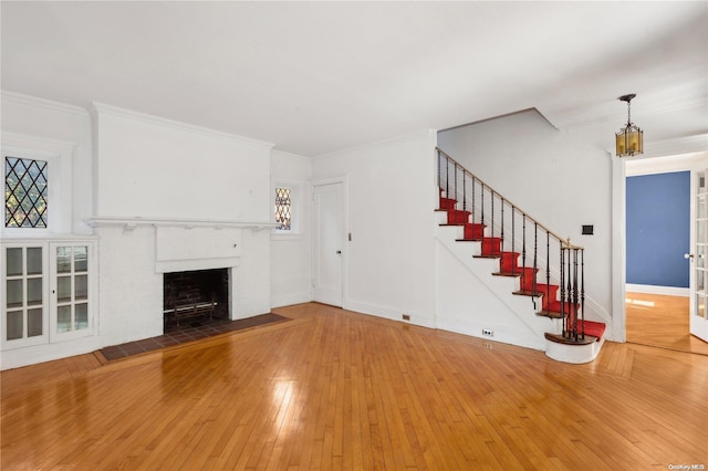 unfurnished living room featuring a fireplace, hardwood / wood-style floors, crown molding, and a healthy amount of sunlight