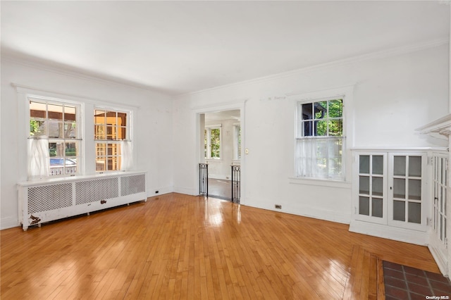 unfurnished living room with radiator, crown molding, and hardwood / wood-style flooring