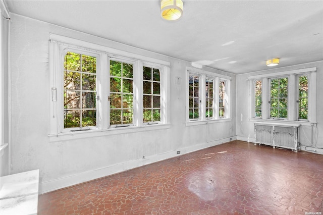 unfurnished sunroom with radiator heating unit