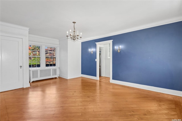 spare room featuring ornamental molding, light hardwood / wood-style floors, radiator, and a notable chandelier