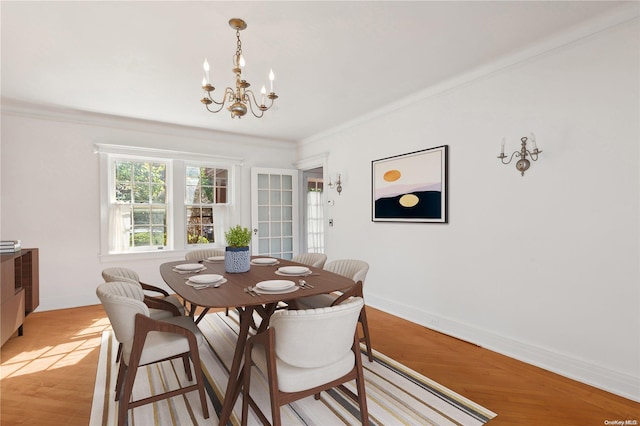 dining area featuring ornamental molding, light wood-type flooring, and a notable chandelier