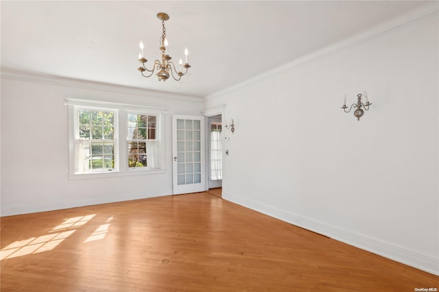 spare room featuring a notable chandelier, wood-type flooring, and ornamental molding