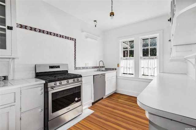 kitchen featuring appliances with stainless steel finishes, light wood-type flooring, white cabinetry, and sink