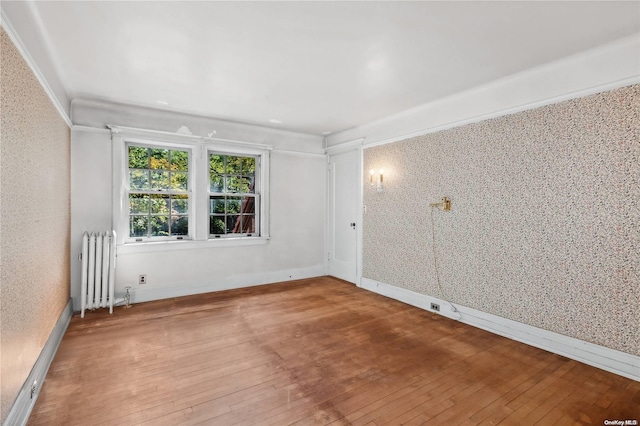 spare room featuring radiator heating unit and wood-type flooring