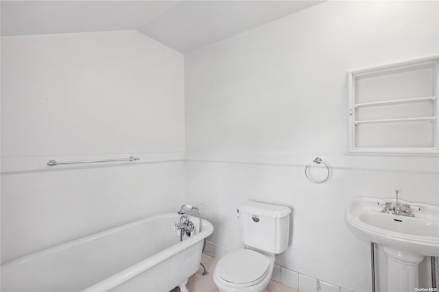 bathroom with a washtub, toilet, and vaulted ceiling