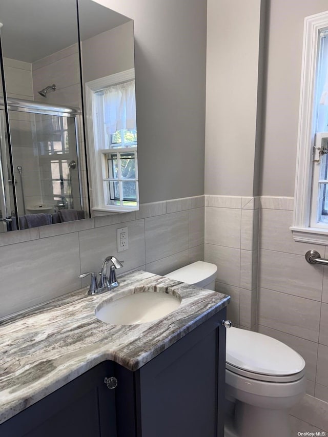 bathroom featuring toilet, vanity, tile walls, and walk in shower