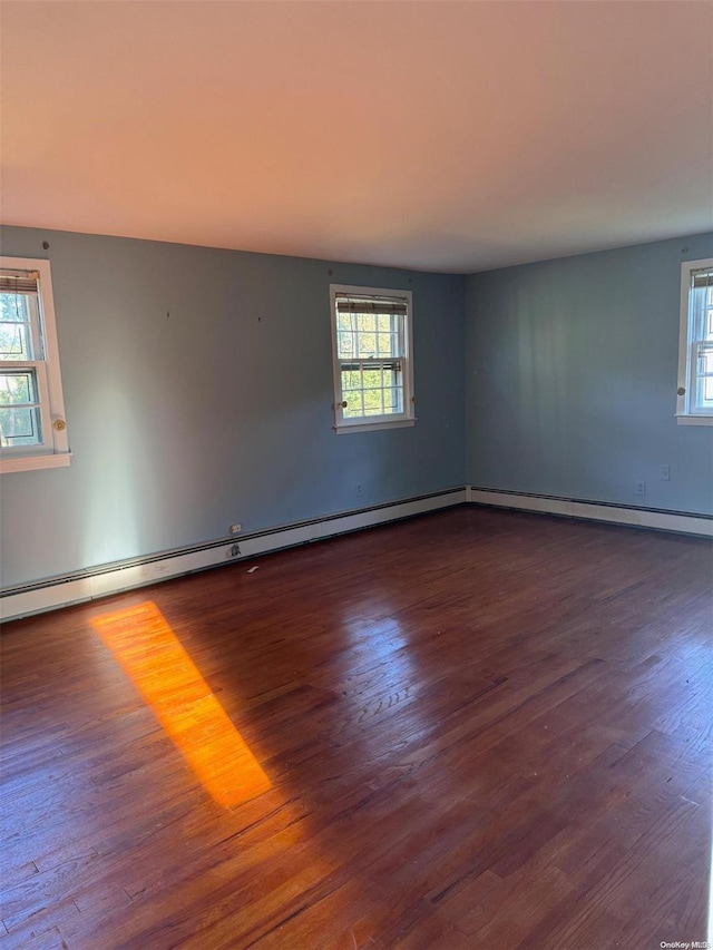 unfurnished room featuring dark hardwood / wood-style flooring, a healthy amount of sunlight, and a baseboard radiator