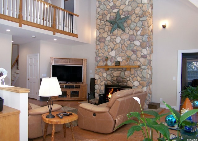 living room featuring a high ceiling, hardwood / wood-style flooring, and a stone fireplace