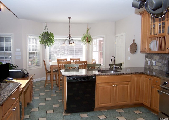 kitchen with dishwasher, dark stone counters, sink, hanging light fixtures, and tasteful backsplash