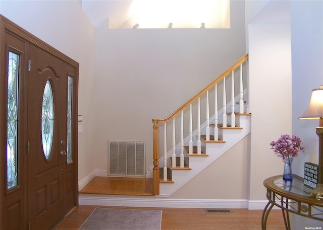 entryway with wood-type flooring and a high ceiling