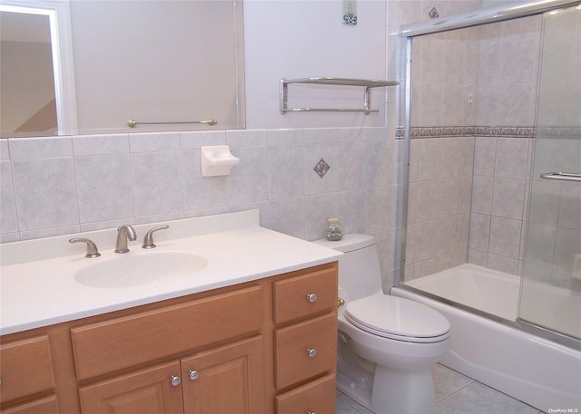 full bathroom with vanity, shower / bath combination with glass door, tile walls, tile patterned flooring, and toilet