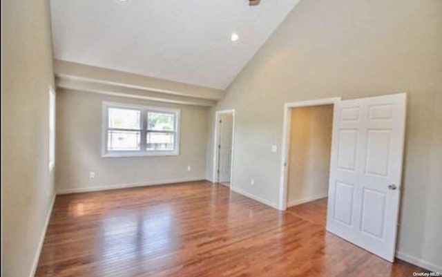 spare room with wood-type flooring and vaulted ceiling