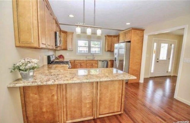 kitchen featuring decorative light fixtures, hardwood / wood-style floors, kitchen peninsula, light stone countertops, and stainless steel appliances