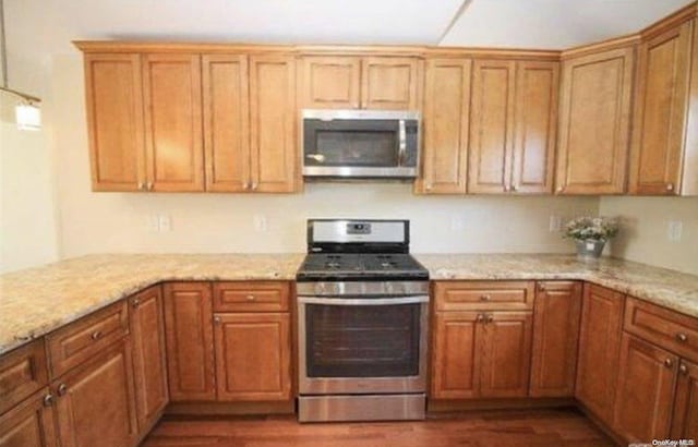 kitchen with stainless steel appliances, dark hardwood / wood-style floors, and light stone countertops