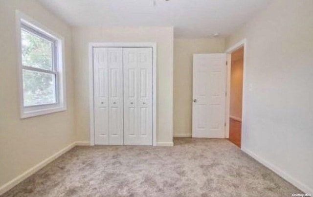 unfurnished bedroom featuring light colored carpet and a closet