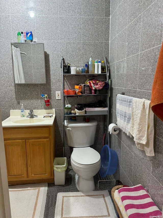 bathroom featuring vanity, toilet, and tile walls