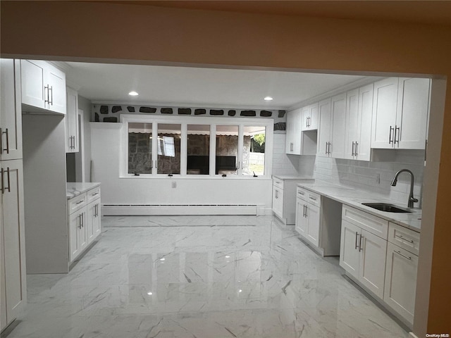 kitchen featuring light stone counters, white cabinetry, sink, and a baseboard heating unit