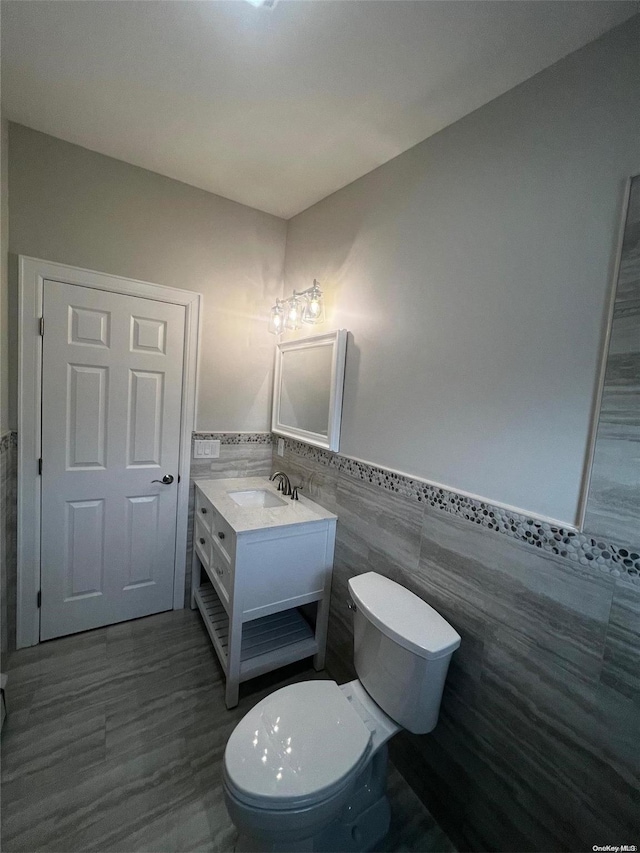 bathroom with vanity, toilet, and tile walls