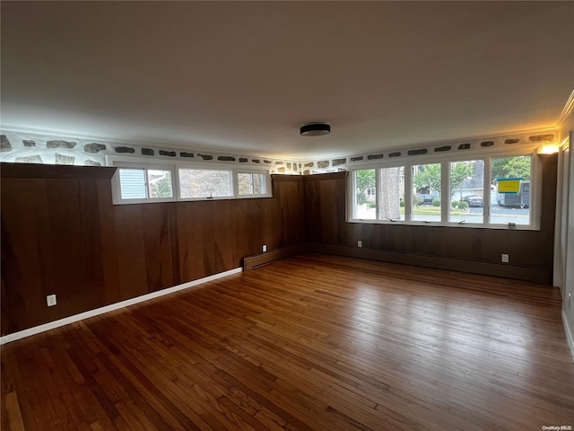 spare room with hardwood / wood-style floors, a baseboard heating unit, and wooden walls