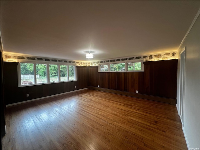 unfurnished room featuring baseboard heating, wooden walls, and hardwood / wood-style floors