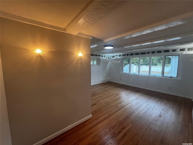 empty room featuring beam ceiling, wood-type flooring, a textured ceiling, and a baseboard radiator