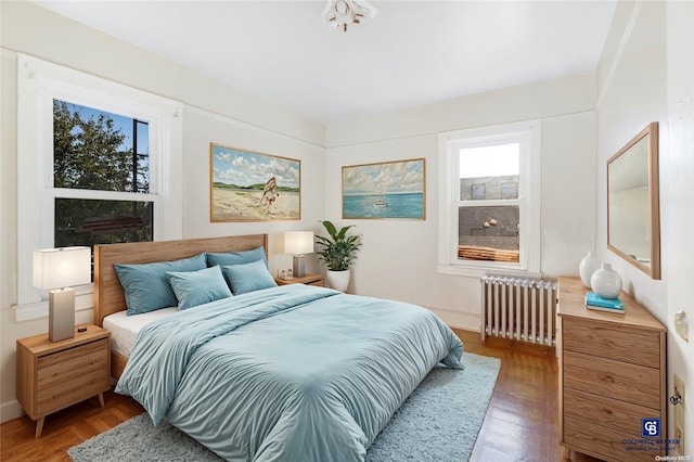 bedroom featuring radiator heating unit and hardwood / wood-style floors