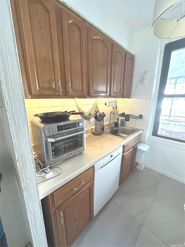 kitchen featuring white dishwasher, light tile patterned floors, sink, and tasteful backsplash