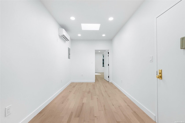 hallway featuring a wall unit AC, a skylight, electric panel, and light hardwood / wood-style floors