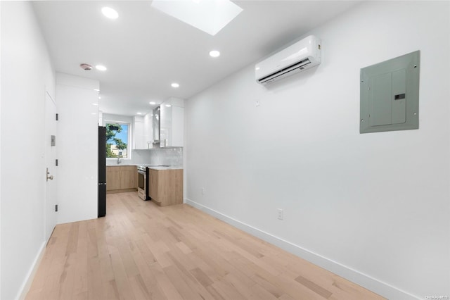 interior space featuring stainless steel range with electric stovetop, electric panel, white cabinets, an AC wall unit, and light wood-type flooring