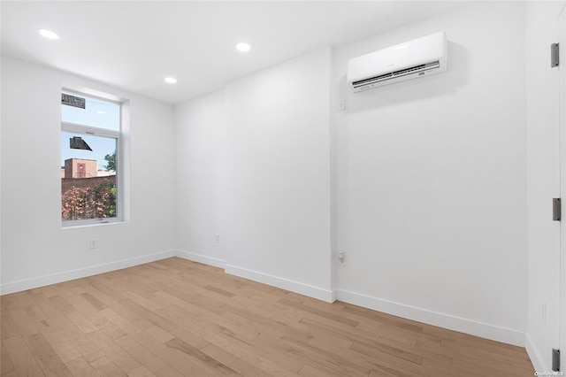 empty room featuring a wall mounted air conditioner and light wood-type flooring