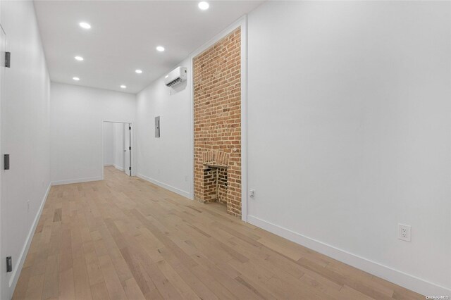 corridor featuring a wall mounted air conditioner, light wood-type flooring, and brick wall